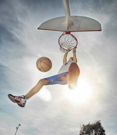 a young man dunking a basketball in the air with his legs and feet up