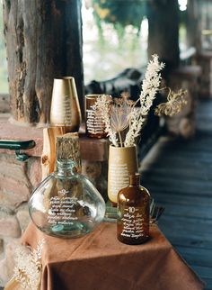 three vases with flowers in them sitting on a table next to a stone wall