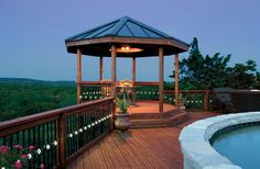 a gazebo sitting on top of a wooden deck next to a hot tub filled with water