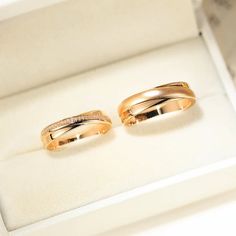 two gold wedding rings sitting in a box