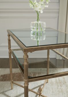 a glass and metal table with flowers on top