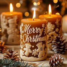 three lit candles with merry christmas decorations on them and pine cones in the foreground