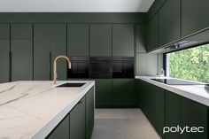 a kitchen with green cabinets and marble counter tops, along with a sink in the middle