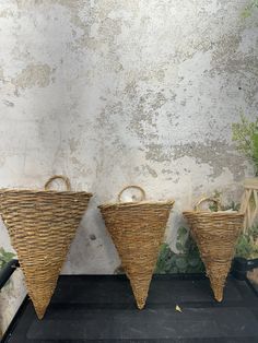 three woven baskets sitting next to each other on a black shelf in front of a white wall