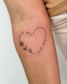 a woman's arm with a tattoo on it that says love and has flowers in the shape of a heart