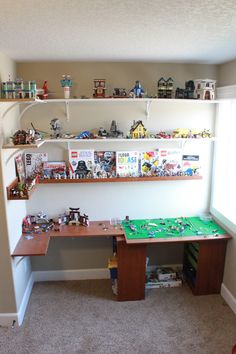 a room with shelves filled with toys and other items on the wall, along with a green table