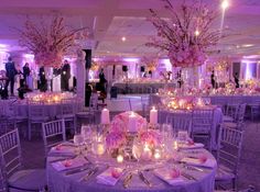 the tables are set with candles and centerpieces for an elegant wedding reception in purple hues