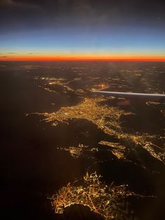 an aerial view of the city lights at night as seen from inside an airplane window