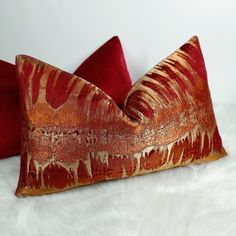 two red and gold pillows on white fur