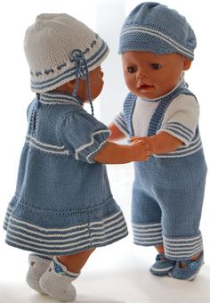 two dolls are standing next to each other wearing knitted clothes and hats, one is holding the baby's hand