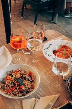 a wooden table topped with plates of food and glasses of wine on top of it