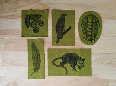 four coasters with animals and plants on them sitting on a wooden table next to each other