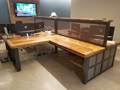 an office with two desks and a monitor on the wall in front of it