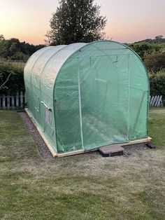 a large green house sitting on top of a lush green field