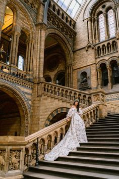 a woman in a long white dress standing on some stairs