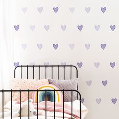 a child's bed with purple hearts on the wall