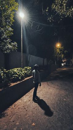 a man standing on the side of a road at night