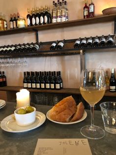 a table topped with wine glasses and plates filled with food next to bottles of wine