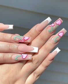 a woman's hand with pink and white nail designs on her nails, holding onto the