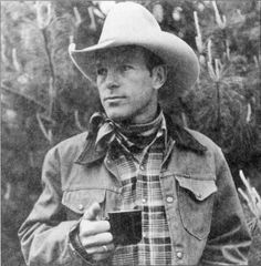 black and white photograph of a man wearing a cowboy hat holding a drink in his hand