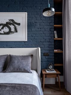 a blue brick wall in a bedroom with a bed and night stand next to it