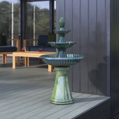 a green water fountain sitting on top of a wooden deck