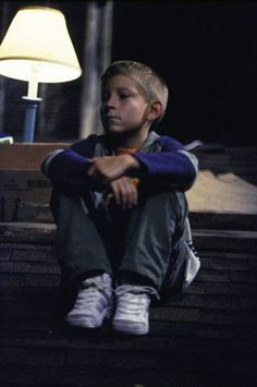 a young boy sitting on steps next to a lamp