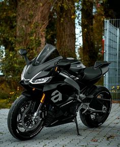 a black motorcycle parked in front of some trees