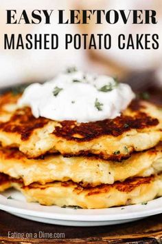 a stack of mashed potato cakes on a white plate with sour cream and herbs