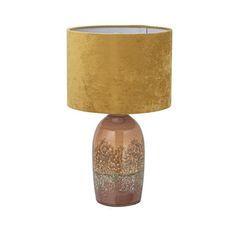 a table lamp with a gold shade on top and a brown base, sitting next to a white wall