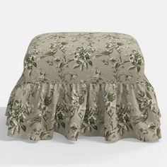 a small stool with a flower pattern on the cover and ruffles at the bottom