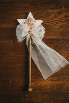 a wooden stick with a white bow on it sitting on top of a wood table