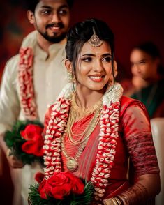 a man and woman standing next to each other with red roses in their hands,