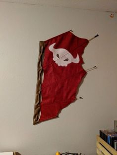 an upside down kite hanging on the wall next to a pile of books and other items