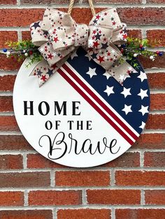 a patriotic sign hanging on the side of a brick wall that says home of the brave