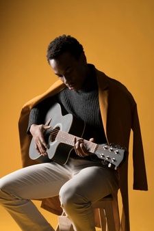 a man sitting on a chair playing an acoustic guitar