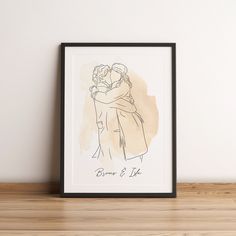 a drawing of two people hugging each other on a shelf next to a framed photograph