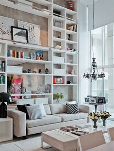 a living room filled with white furniture and lots of bookshelves on the wall