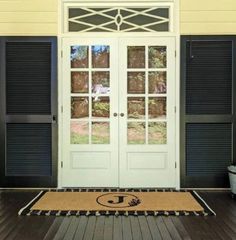 the front door is decorated with black shutters and a monogrammed welcome mat