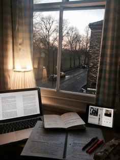 an open book sitting on top of a desk next to a laptop computer and lamp