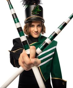 a woman in a green uniform holding two white and black sticks while wearing a hat