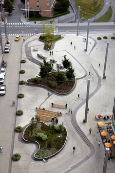 an aerial view of people walking and sitting on benches in the middle of a street