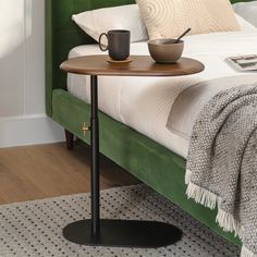 a table with a cup on it next to a green headboard in a bedroom