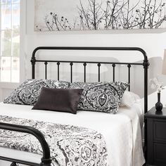 a black and white bedroom with a metal headboard, night stand, and painting on the wall