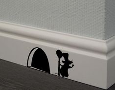 a mouse sticker on the side of a wall next to a door with it's shadow