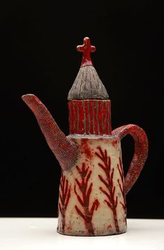 a red and white tea pot with a bird on top