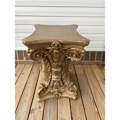 an ornate gold pedestal on a wooden deck