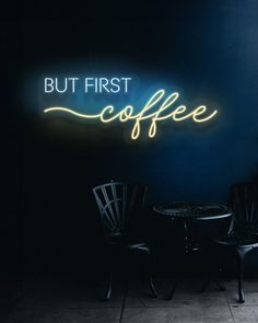 two chairs sitting in front of a neon sign that says but first coffee