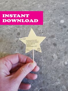 a hand holding a small wooden star on top of a white stick that says instant download