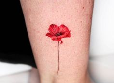 a single red flower on the side of a woman's leg